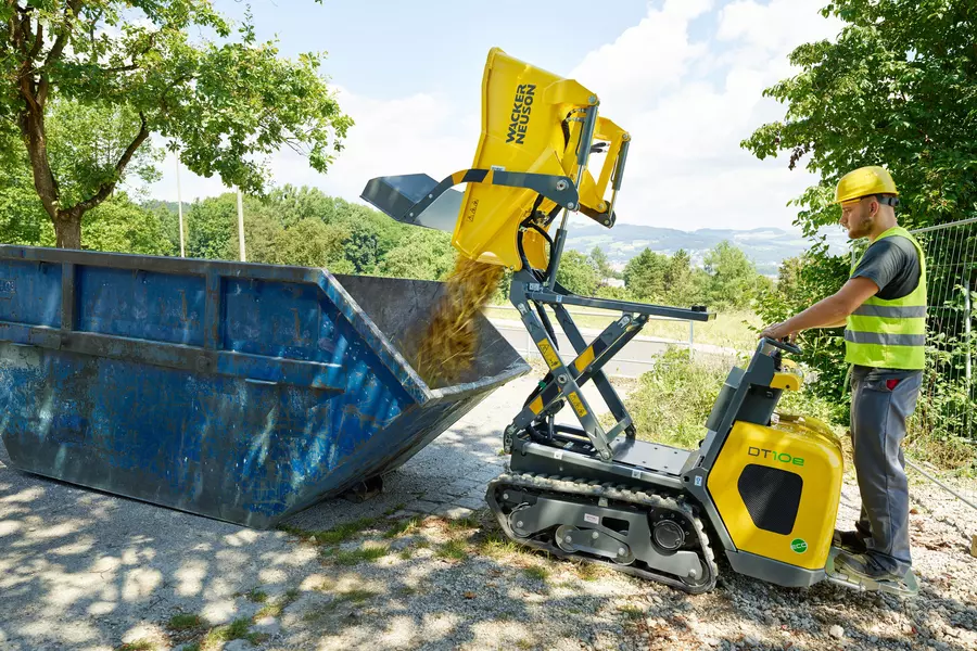 DT10e Kettendumper beim Abladen in einen Container mittels Hochkippmulde
