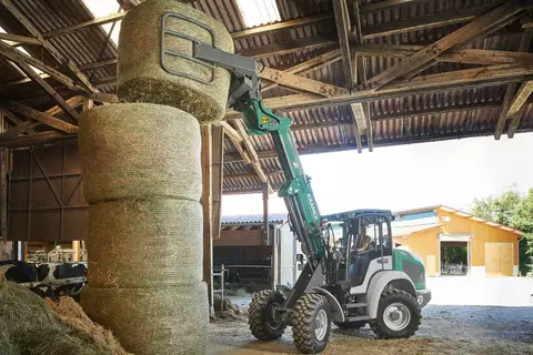 The Kramer telescopic wheel loader KL25.5T while loading bales on a field. 