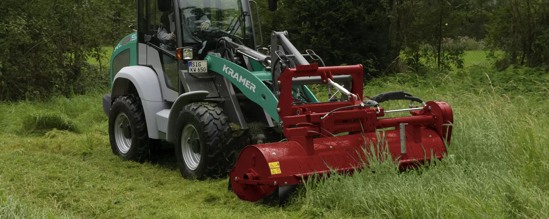 The Kramer wheel loader KL25.5 while doing mowe work on a  meadow.