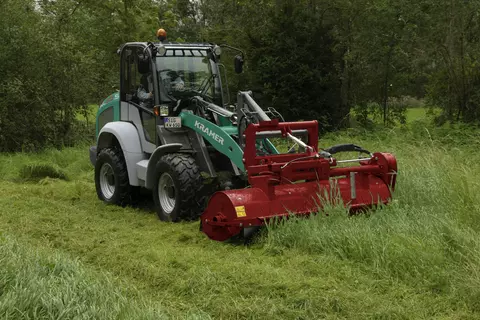 The Kramer wheel loader KL25.5 while doing mowe work on a  meadow.