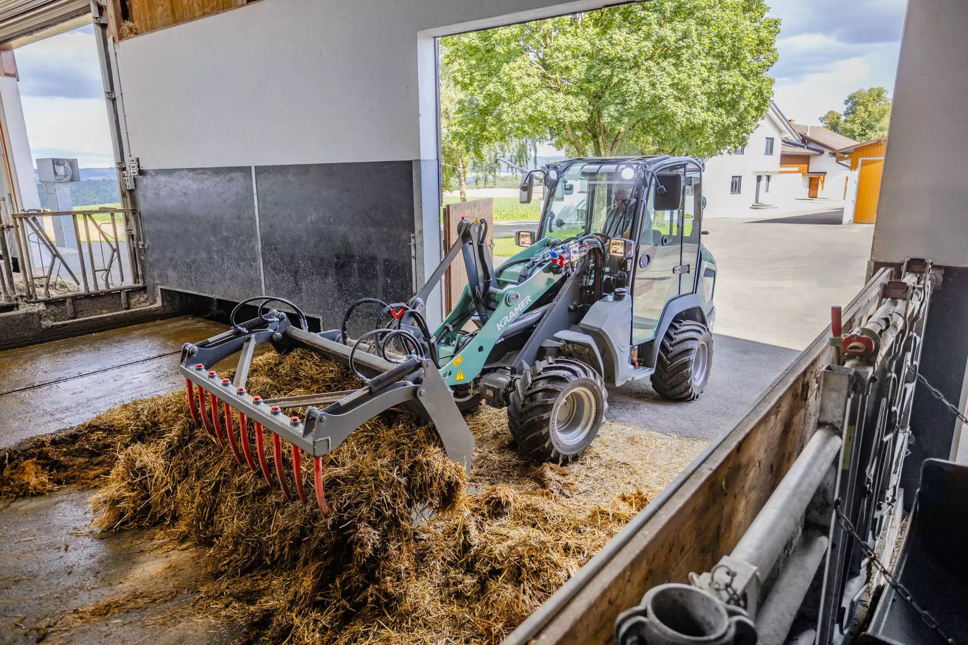 Der Kramer Radlader KL21.5L ist bei der Arbeit mit Silage in einer landwirtschaftlichen Umgebung im Einsatz.