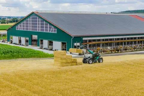 Der Kramer Teleskoplader KT316 zeigt seine Stärken beim Transport von Strohballen auf dem Hof.