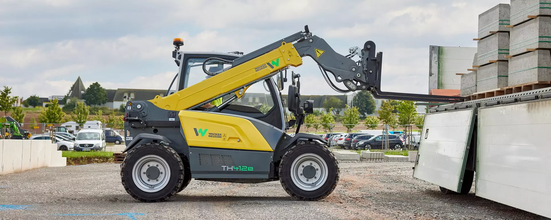 Wacker Neuson Teleskoplader TH412e im Einsatz auf einer Baustelle mit Palettengabel